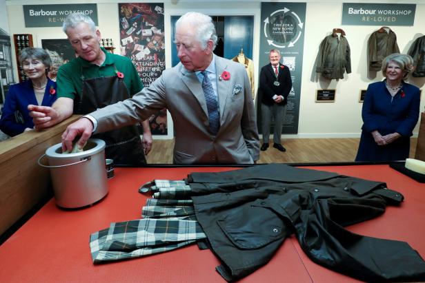 König Charles bei einem Barbour Workshop, wo er eine Jacke pflegt.