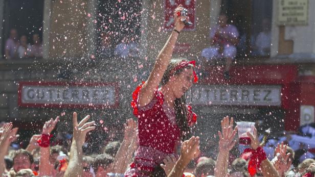 Eine junge Frau wird auf den Schultern getragen, während Konfetti in der Luft schwebt.