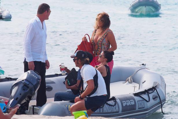 Eine Gruppe von Personen steigt in ein graues Schlauchboot am Strand.