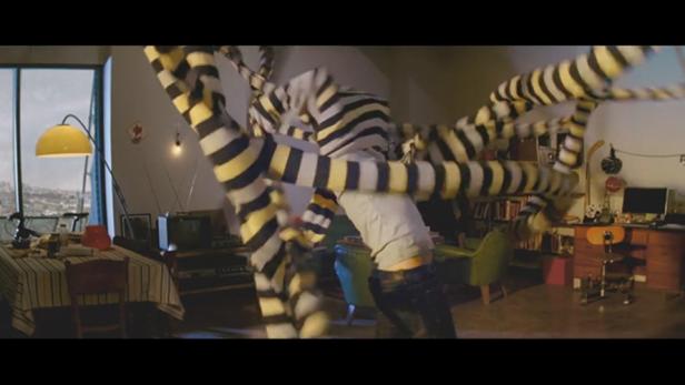Ein Mann wird von einem Tentakelwesen mit Zebra-Streifen angegriffen.