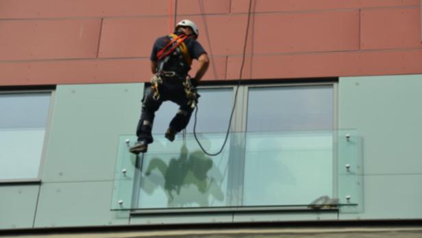 Ein Fensterputzer seilt sich von einem Gebäude ab.
