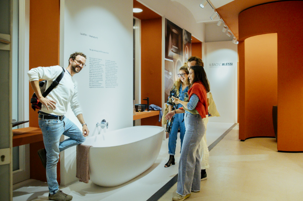 Eine Gruppe von Leuten betrachtet eine Badewanne in einem Ausstellungsraum.