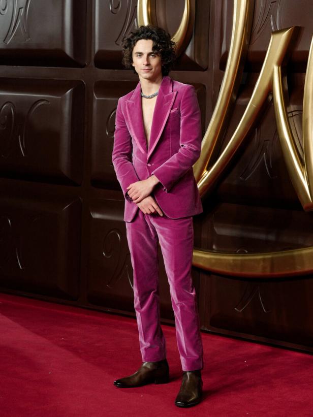 Timothée Chalamet in einem pinkfarbenen Anzug auf einem roten Teppich.