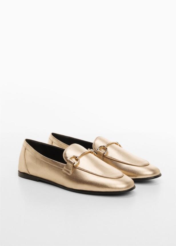 Ein Paar goldene Slipper mit Zierspangen stehen auf einem weißen Hintergrund.