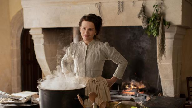 Juliette Binoche steht in „Geliebte Köchin“ in einer historischen Küche am Herd.