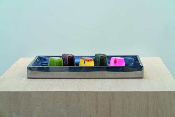 Fünf farbige, würfelförmige Objekte in einer Metallschale, Werk von Rirkrit Tiravanija, „untitled 2019 (five easy pieces)“.