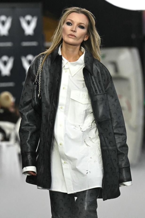 Kate Moss auf dem Laufsteg in einem schwarzen Outfit mit Halbmondmuster.