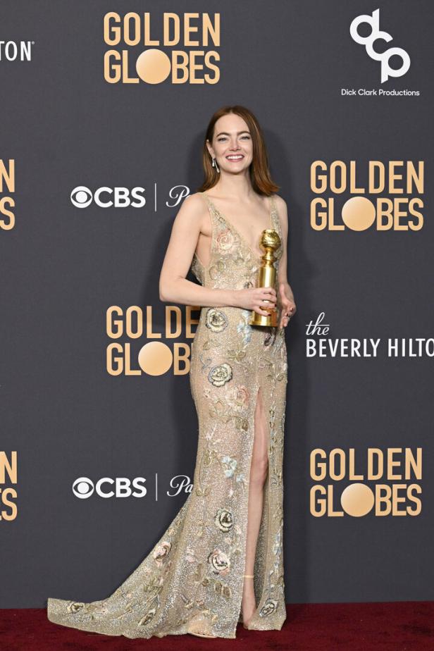 Emma Stone hält eine Golden Globe-Trophäe in einem mit Blumen bestickten Kleid.