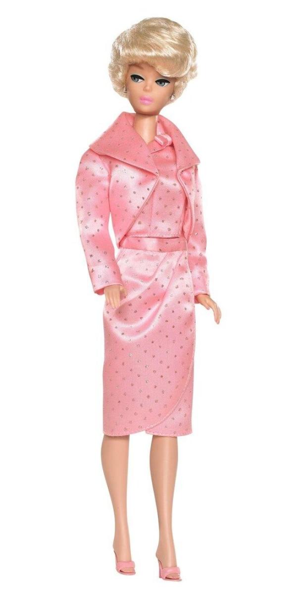 Eine Barbie-Puppe trägt ein rosa Kostüm mit Jacke und Rock.