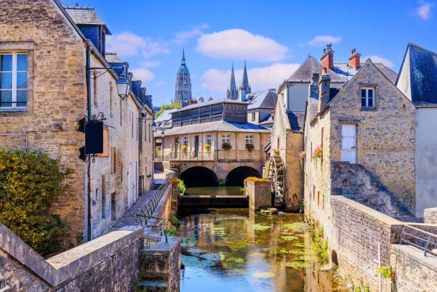 Ein malerischer Kanal schlängelt sich durch eine mittelalterliche Stadt mit alten Steinhäusern.