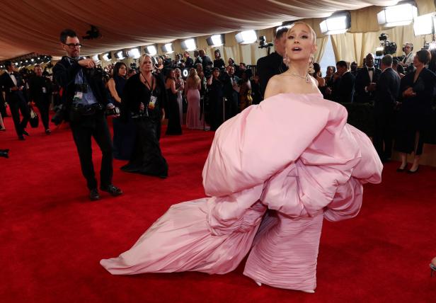 Ariana Grande in einem auffälligen, rosa Kleid auf einem roten Teppich.