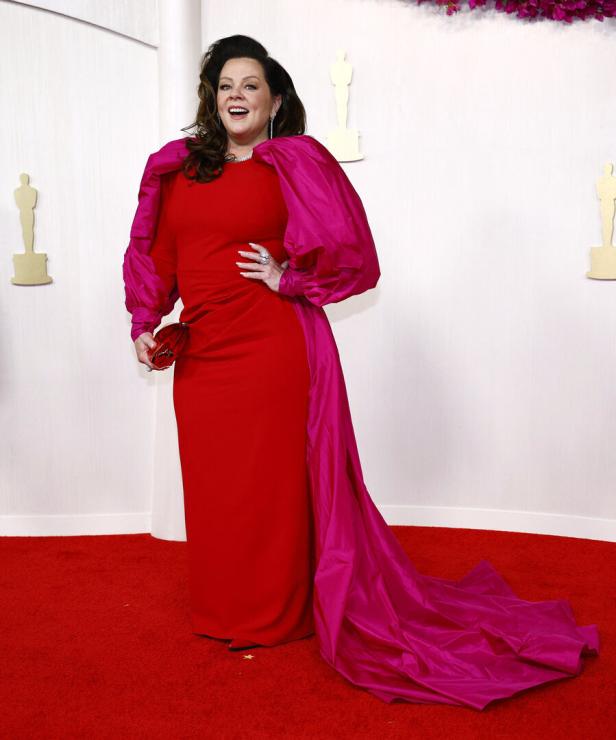 Melissa McCarthy in einem roten Kleid mit pinkfarbenen Ärmeln auf dem roten Teppich.