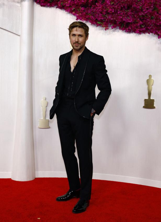 Ryan Gosling posiert auf dem roten Teppich in einem schwarzen Anzug.