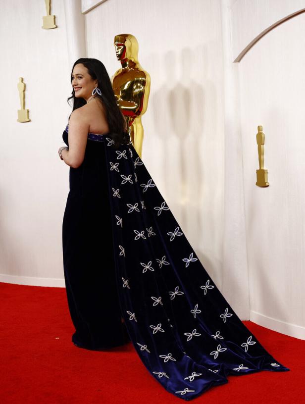Eine Frau in einem blauen Kleid mit Blumenmuster auf dem roten Teppich.