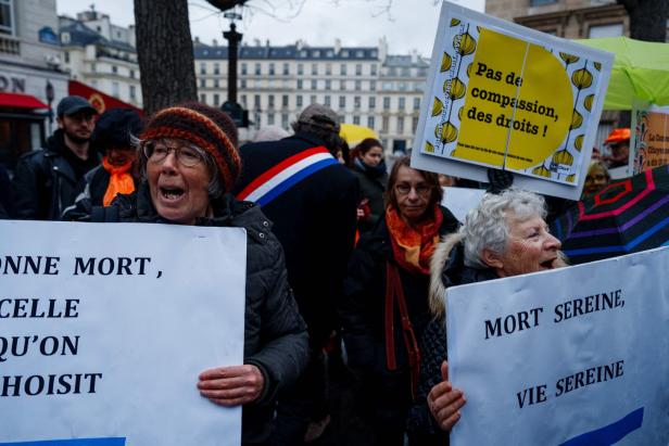 Frauen halten Plakate mit der Aufschrift "Ruhiger Tod, ruhiges Leben" und "Kein Mitleid für Rechte" während einer Pro-Euthanasie-Demonstration in Paris am 23. Januar 2024.