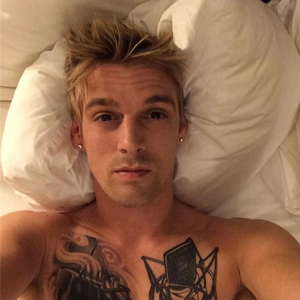 Aaron Carter liegt mit Tätowierungen auf der Brust im Bett.