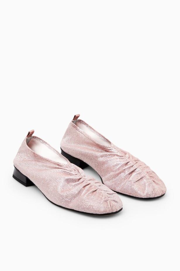 Zwei rosafarbene, geraffte Ballerinas mit kleinem Absatz stehen auf einem weißen Hintergrund.