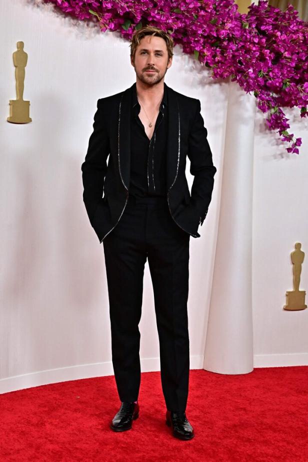 Ryan Gosling posiert auf dem roten Teppich in einem schwarzen Anzug.