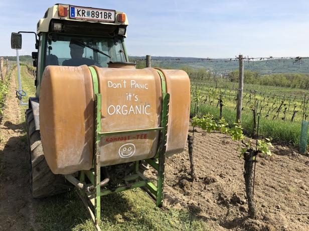Ein Traktor mit der Aufschrift „Don't Panic it's ORGANIC“ steht in einem Weinberg.