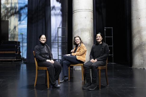 Miriam M., Mercedes M. Vargas und Regisseurin Kornmüller sitzen auf einer Bühne.