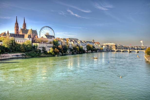Blick auf den Rhein in Basel mit dem Basler Münster und einem Riesenrad.