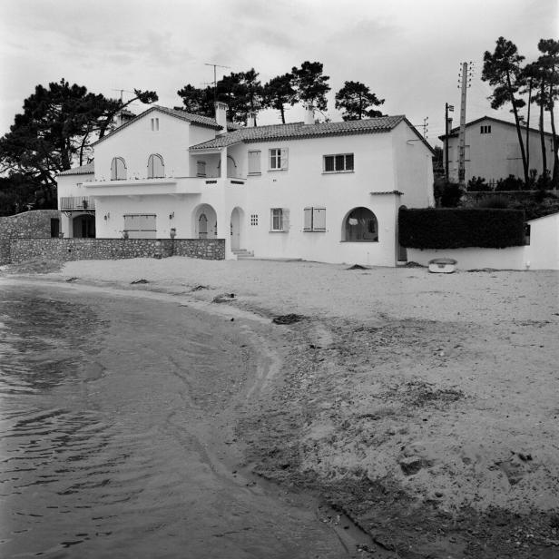 Ein weißes Haus steht am Strand, umgeben von Bäumen.