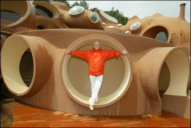Ein Mann steht mit ausgestreckten Armen in einer runden Öffnung des Bubble House.