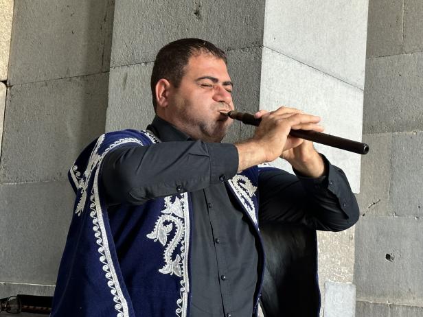 Mann in traditionellem Gewand spielt in Armenien das Nationalinstrument Duduk, eine armenische Flöte