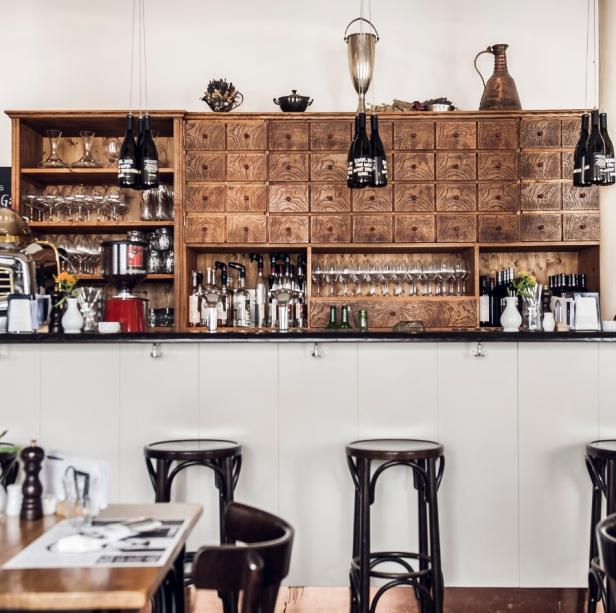 Eine Bar mit Holzhocker und einer Wand voller Schubladen und Spirituosen.