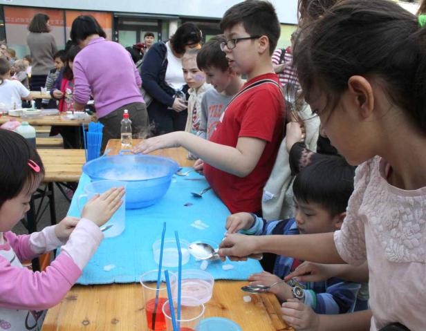 Kinder experimentieren mit Trockeneis in einer blauen Schüssel.