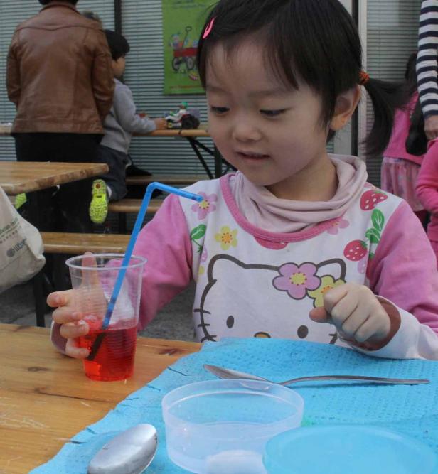 Ein junges Mädchen trinkt mit einem Strohhalm aus einem roten Getränk.