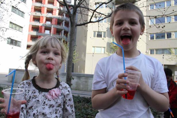 Ein Junge und ein Mädchen halten Getränke mit Strohhalmen und strecken die Zungen heraus.