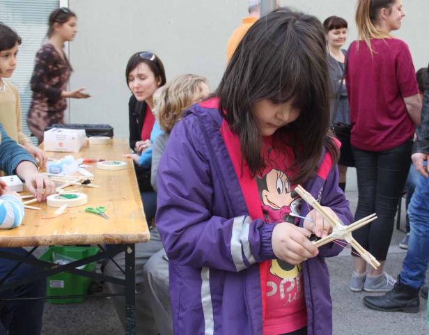Ein junges Mädchen bastelt mit Holzstäben und Gummibändern.