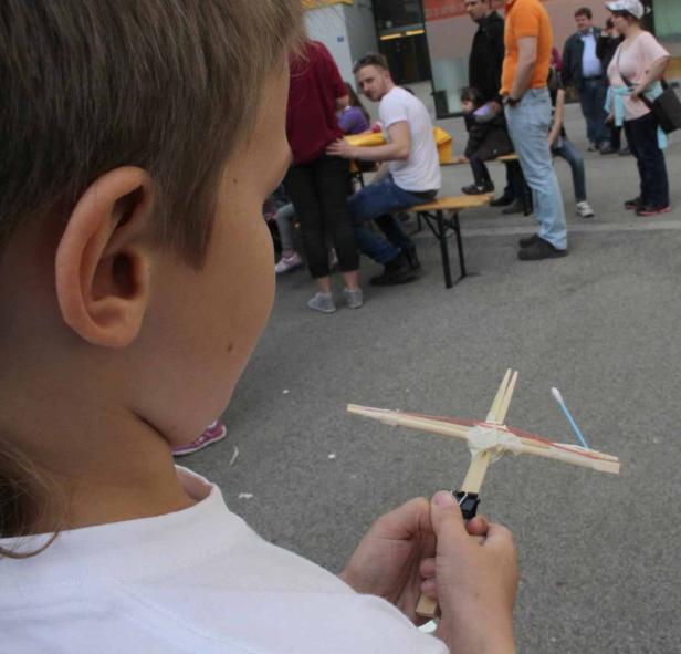 Ein Junge hält eine selbstgebaute Armbrust aus Holz und Gummibändern in den Händen.