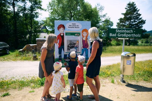 Eine Familie betrachtet ein Schild in der Natur.
