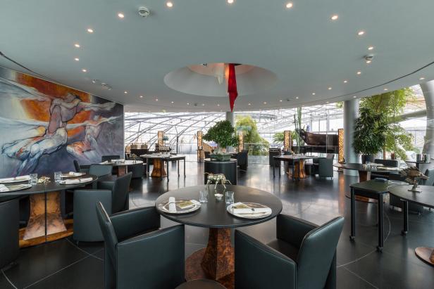 Innenansicht des Restaurants Ikarus im Hangar-7 mit Tischen und Kunstwerken.