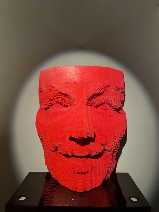 Eine rote Skulptur eines Gesichtes, gebaut aus Legosteinen.