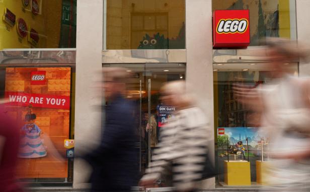 Verschwommene Menschen vor einem Lego-Geschäft mit Schaufenstern und dem Lego-Logo.