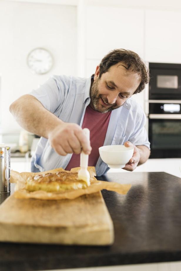 Ein Mann bestreicht einen Kuchen mit einem Pinsel.