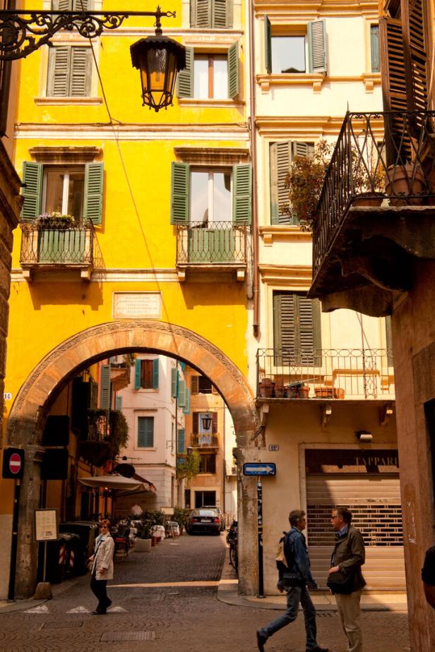 Ein belebter Blick durch einen Torbogen auf eine Gasse in Verona, Italien.