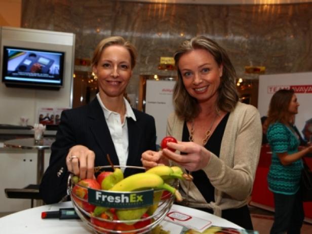 Zwei Frauen stehen an einem Stand mit einem Korb voller Obst.