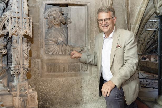 Ein Mann posiert neben einer Skulptur in einem historischen Gebäude.