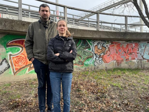 Ein Mann und eine Frau stehen vor einer mit Graffiti bemalten Wand.