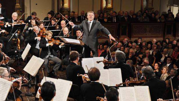 Ein Dirigent leitet ein Orchester vor einem Publikum.