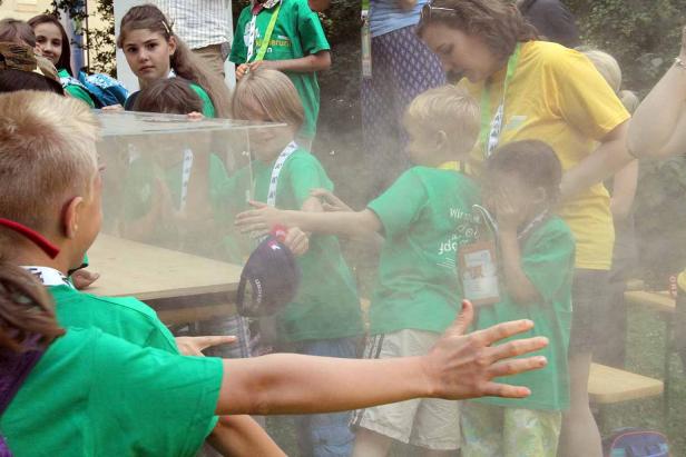 Eine Gruppe Kinder experimentiert mit einer Nebelkammer im Freien.