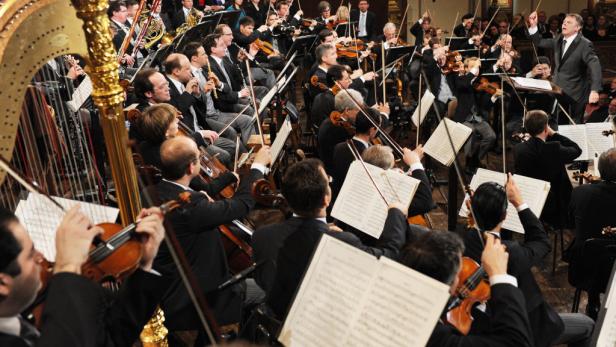 Ein Orchester spielt unter der Leitung eines Dirigenten in einem Konzertsaal.