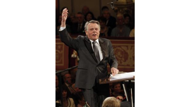 Ein Dirigent leitet ein Orchester mit erhobenem Arm.