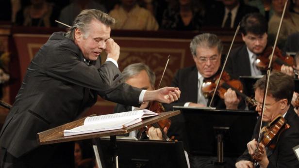 Ein Dirigent leitet ein Orchester mit mehreren Geigenspielern.