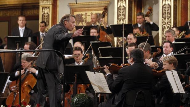 Ein Dirigent leitet ein Orchester in einem Konzertsaal.