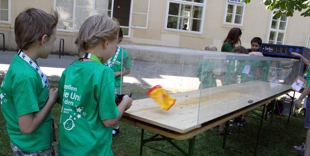 Kinder steuern ein ferngesteuertes Auto in einem transparenten Behälter.